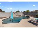 Backyard view of a private in-ground pool with a rock waterfall feature and lounge seating at 1057 E Silversmith Trl, San Tan Valley, AZ 85143