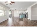 Open-concept living room and kitchen with wood floors, stainless steel appliances, and two ceiling fans at 19318 E Reins Rd, Queen Creek, AZ 85142