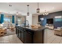 Open concept kitchen features an island with granite countertops and modern pendant lighting at 2410 S 124Th Dr, Avondale, AZ 85323