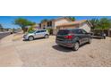 Exterior view of a home showing the driveway and front yard with two parked cars and gravel landscaping at 7259 E Glencove St, Mesa, AZ 85207