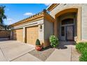 Attractive exterior with a three-car garage and arched entry with decorative glass door at 10897 S Turtle Dove S Dr, Goodyear, AZ 85338