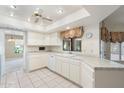 Clean kitchen featuring white cabinetry, tile countertops, and floral window treatments at 1338 E Greenway Cir, Mesa, AZ 85203