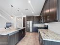 Modern kitchen featuring stainless steel appliances, granite countertops, tiled flooring, and dark wood cabinetry at 24776 N 171St Ln, Surprise, AZ 85387
