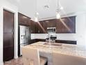 Well-lit kitchen boasts stainless appliances, a granite island with seating, and stylish dark wood cabinets at 24776 N 171St Ln, Surprise, AZ 85387