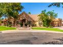 Charming stone home featuring a circular driveway, fountain, and lush green landscaping at 2558 E Page Ct, Gilbert, AZ 85234