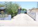 Long driveway next to a single story home leading to a green fence and trash receptacle at 2718 W Montebello Ave, Phoenix, AZ 85017