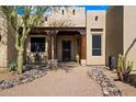 Inviting home front entrance with custom wood detailing, desert landscaping, and a charming seating area at 27203 N 64Th Way, Scottsdale, AZ 85266