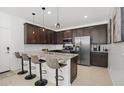Contemporary kitchen boasts stainless steel appliances, a granite island with seating, and sleek, dark-stained cabinets at 29431 N 122Nd Gln, Peoria, AZ 85383