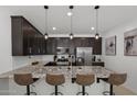 Modern kitchen with stainless steel appliances, granite counters, and dark cabinetry, complemented by stylish pendant lighting at 29431 N 122Nd Gln, Peoria, AZ 85383