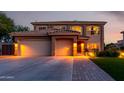 Two-story home with a three-car garage and illuminated driveway, featuring a tile roof and well-manicured landscaping at 9569 W Redbird Rd, Peoria, AZ 85383