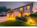 Charming two-story home with a welcoming front porch and meticulously maintained landscaping with illuminated walkway at 9569 W Redbird Rd, Peoria, AZ 85383