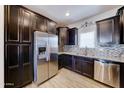 Well-equipped kitchen with stainless steel refrigerator, granite countertops, tile backsplash, and dark cabinets at 16389 N 180Th Dr, Surprise, AZ 85388