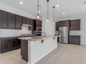 Modern kitchen featuring dark cabinets, granite countertops, stainless steel appliances, and pendant lighting at 22788 E Orion Way, Queen Creek, AZ 85142