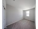 An empty bedroom with neutral carpeting and a window providing natural light at 18260 W Daley Ln, Surprise, AZ 85387