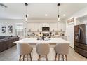 Bright kitchen boasts a large island with seating, white cabinets and stainless steel appliances at 11951 W Wier Ave, Avondale, AZ 85323