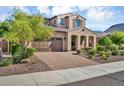 Two-story home with desert landscaping featuring blooming tree, tile roof, and a two-car garage at 12932 W Cassia Trl, Peoria, AZ 85383