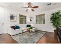 Bright living room with hardwood floors, a white sofa, a decorative rug, and a ceiling fan with a light fixture at 17862 N 114Th Ln, Surprise, AZ 85378