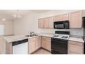 This kitchen features black appliances, light wood cabinets, and modern finishes at 205 N 74Th St # 110, Mesa, AZ 85207