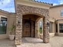 Inviting front entrance with stone columns, a wooden arched door, lanterns, and a brick pathway at 3804 E Camelback Rd, Phoenix, AZ 85018