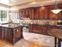 Gourmet kitchen boasts dark wood cabinets, granite countertops, stainless steel appliances, and tile flooring at 3804 E Camelback Rd, Phoenix, AZ 85018