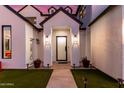 An inviting entrance featuring a dark front door, minimalist potted plants, and a sleek gray walkway at 4131 E Roma Ave, Phoenix, AZ 85018