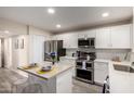 Modern kitchen featuring white cabinetry, stainless steel appliances, and an island with seating at 10516 W Peoria Ave, Sun City, AZ 85351