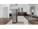 Kitchen showcasing stainless steel refrigerator, white cabinets, updated backsplash, and sink with countertop space at 14981 W Robson N Cir, Goodyear, AZ 85395