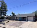Charming single-story home featuring a well-manicured desert front yard, a bright blue front door, and a brick paved driveway at 3615 E Hearn Rd, Phoenix, AZ 85032
