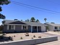 Charming single-story home featuring a well-manicured desert front yard, a bright blue front door, and a brick paved driveway at 3615 E Hearn Rd, Phoenix, AZ 85032
