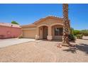 Charming single-story home featuring a desert landscape, a mature palm tree, and a two-car garage at 674 E Renegade Pl, San Tan Valley, AZ 85143