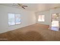 Bright and airy living room with neutral carpet, ceiling fan, and ample natural light from large windows at 674 E Renegade Pl, San Tan Valley, AZ 85143