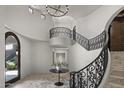 Elegant home foyer with a winding staircase, wrought iron railings, and decorative chandelier at 9290 E Thompson Peak Pkwy # 470, Scottsdale, AZ 85255