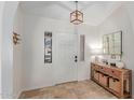 Bright foyer with travertine floors, white walls, a modern light fixture, and wood furniture at 10029 S 44Th St, Phoenix, AZ 85044