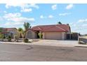 Beautiful single-story home with a red tile roof, lush landscaping, and an attached two-car garage at 1192 E Sunset Dr, Casa Grande, AZ 85122