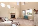 Bright living room with high ceilings, fireplace, plush seating, and large window at 15792 W Desert Mirage Dr, Surprise, AZ 85379