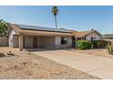 A single-story home with carport and drought-resistant landscaping, showcasing solar panels on the roof at 18818 N 12Th Ave, Phoenix, AZ 85027