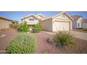 Well-maintained single-story home showcasing desert landscaping, a two-car garage, and a charming front entrance at 19961 N Coyote Lakes Pkwy, Surprise, AZ 85378