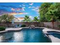 Swimming pool and spa with rock waterfall, lounge chairs, and mature landscaping at 2056 E Carob Dr, Chandler, AZ 85286
