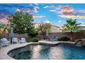 Inviting swimming pool with a rock waterfall, with comfortable seating areas and striped umbrellas at 2056 E Carob Dr, Chandler, AZ 85286