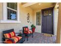 Cozy front porch with two chairs, cushions, and a decorative metal wall sculpture at 20684 W Meadowbrook Ave, Buckeye, AZ 85396