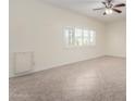 Bright empty room featuring neutral paint, tile floors, baseboards and a ceiling fan plus a view to the exterior at 2547 W Naranja Ave, Mesa, AZ 85202
