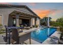 Inviting backyard oasis featuring a sparkling pool, covered patio, and comfortable lounge seating at 26314 N 103Rd Dr, Peoria, AZ 85383