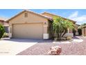 Home exterior featuring a two-car garage, desert landscaping, and tan stucco at 3750 S Conestoga Rd, Apache Junction, AZ 85119