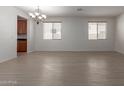 Spacious living room with wood-look floors, natural light, and an elegant chandelier at 7205 W Ellis St, Laveen, AZ 85339