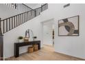 Bright foyer features wood floors, staircase, console table with decorative plants and artwork, and an open hallway to the bathroom at 7616 S Sorrell Ln, Gilbert, AZ 85298