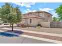 Side view of a well-maintained two-story home with a low wall, featuring desert landscaping at 14161 W Poinsettia Dr, Surprise, AZ 85379
