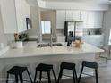 Bright kitchen with white cabinets, quartz countertops, stainless steel appliances and black bar stools at 2213 N Ashbrook Cir, Mesa, AZ 85213