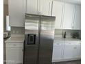 Spacious kitchen featuring stainless steel refrigerator, white cabinets, and quartz countertops at 2213 N Ashbrook Cir, Mesa, AZ 85213