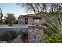 Charming home exterior with stone accents, desert landscaping, and a cozy front patio at 26885 N 104Th Pl, Scottsdale, AZ 85262