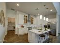 Gourmet kitchen with white cabinets, stainless steel appliances, island with bar stools, and a nearby laundry room at 40927 W Sunland Dr, Maricopa, AZ 85138